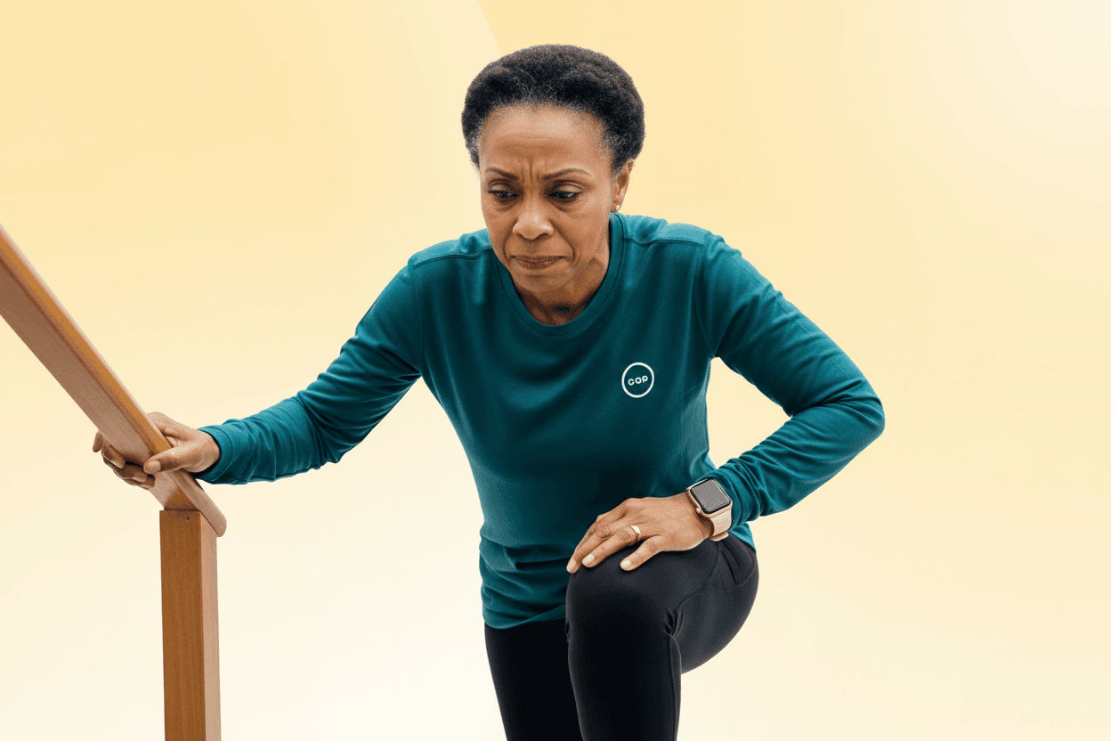 Woman climbing stairs while holding her knee, illustrating knee pain when going upstairs.