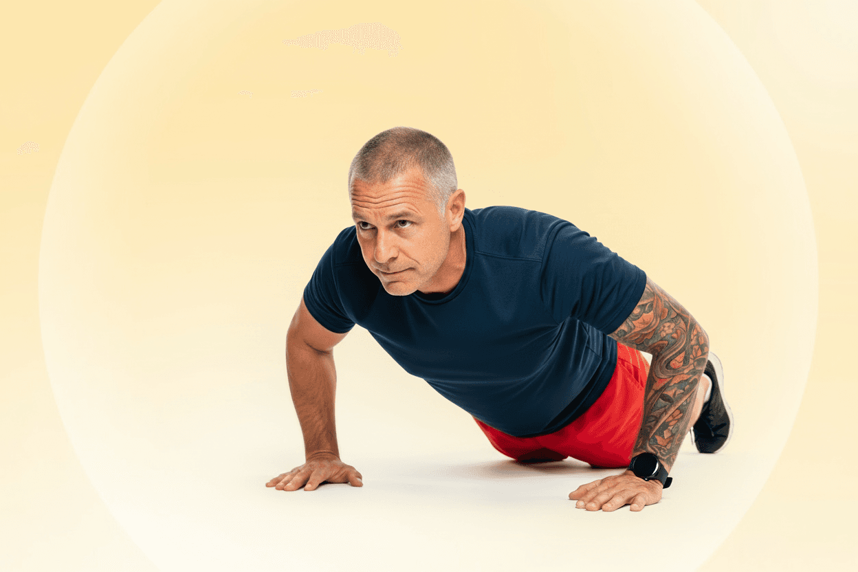 Middle-aged man with sleeve tattoo completes a push up while looking determined