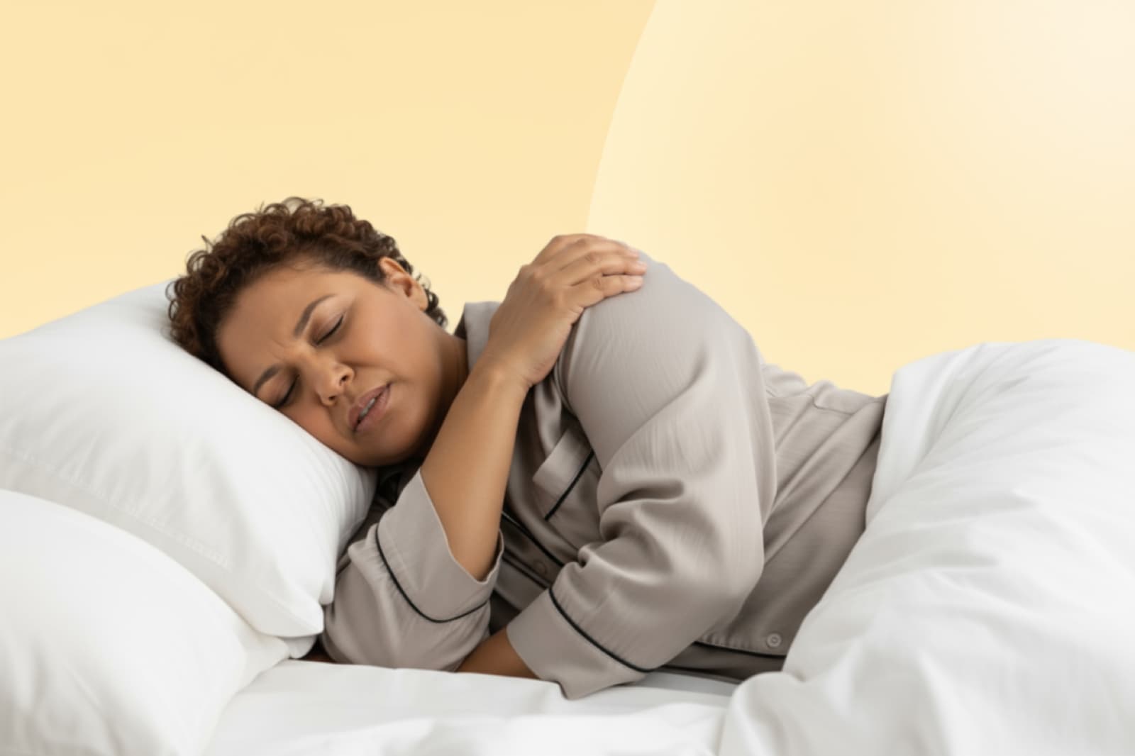 A person sleeps on their side in bed, wearing pajamas, with one hand on their shoulder, against a soft yellow background.