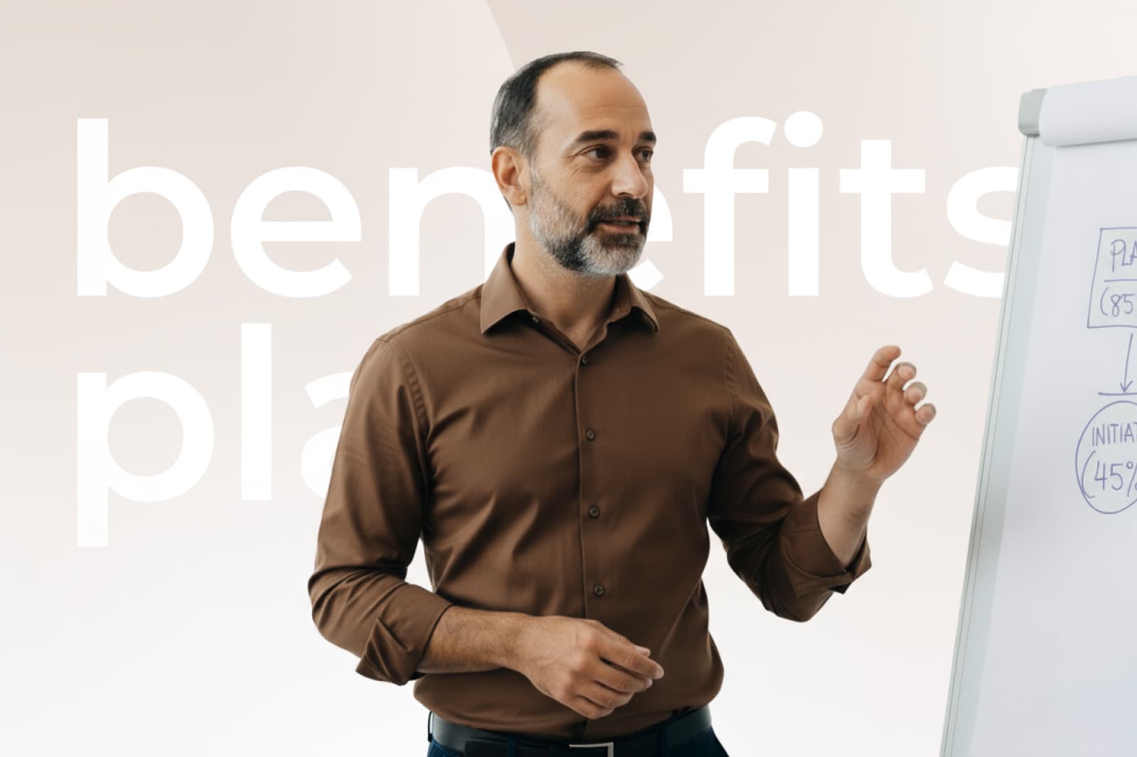 Man in a brown shirt presenting at a whiteboard with diagrams, standing in front of large text partially reading "benefits plan."