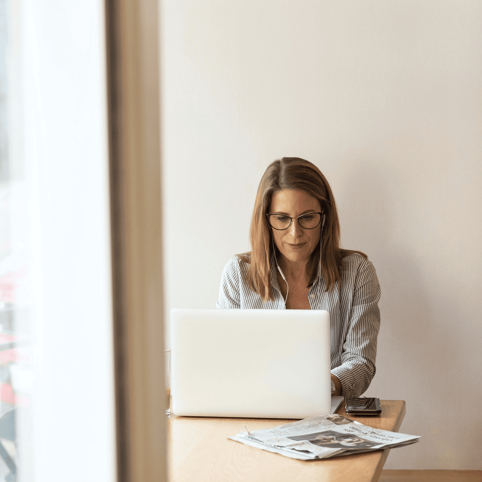 A health plan executive analyzing a healthcare costs report while sitting at an office desk with her laptop