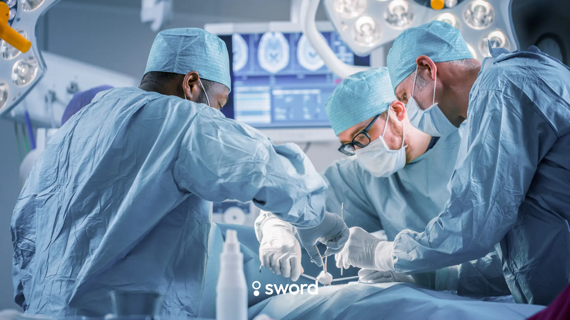 Three surgeons in blue scrubs and masks perform surgery in an operating room, with medical equipment visible in the background.
