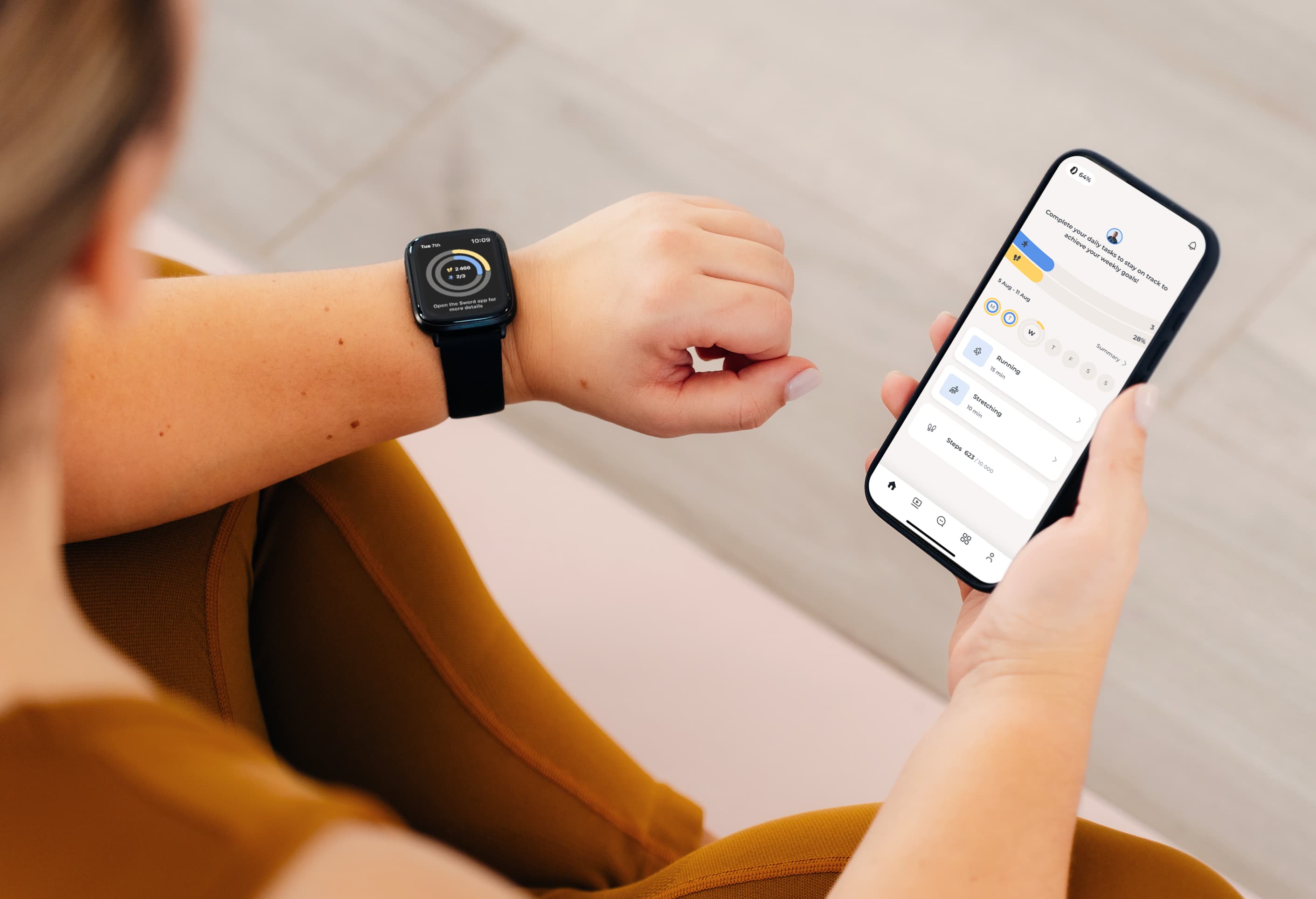 Person checking fitness stats on a Move Wearable smartwatch and smartphone, both displaying health data. They're seated, wearing a brown outfit.