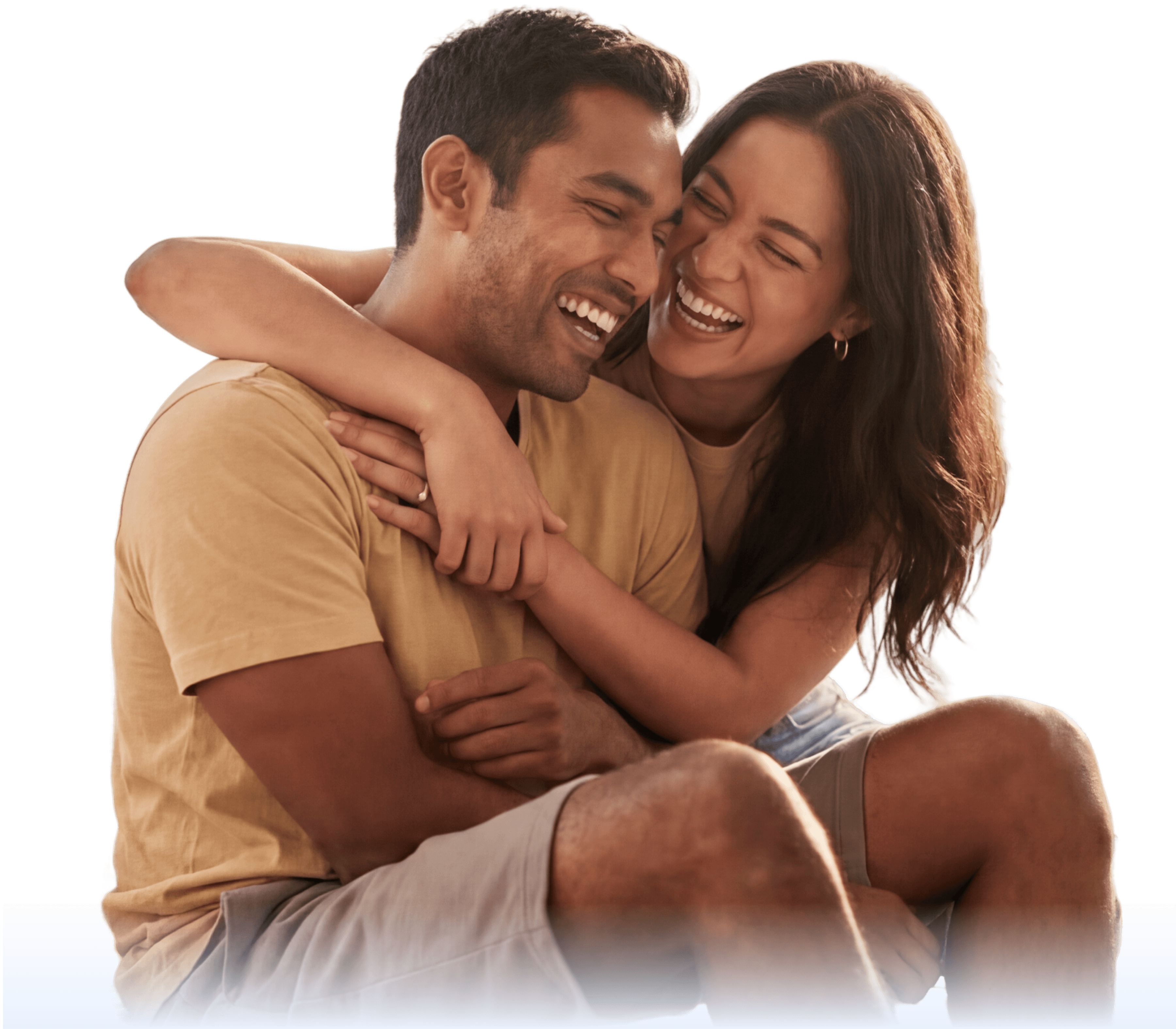 A couple sits close together, smiling and laughing. The woman has her arm around the man, and they appear happy and relaxed, wearing casual clothes on a white background.