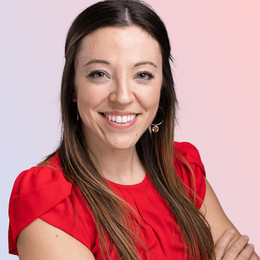 Smiling woman with long brown hair wearing a red blouse, standing against a gradient background of light blue and pink.