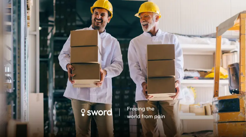 Two workers in hard hats smiling and carrying boxes in a warehouse. Text reads, "Sword: Freeing the world from pain."