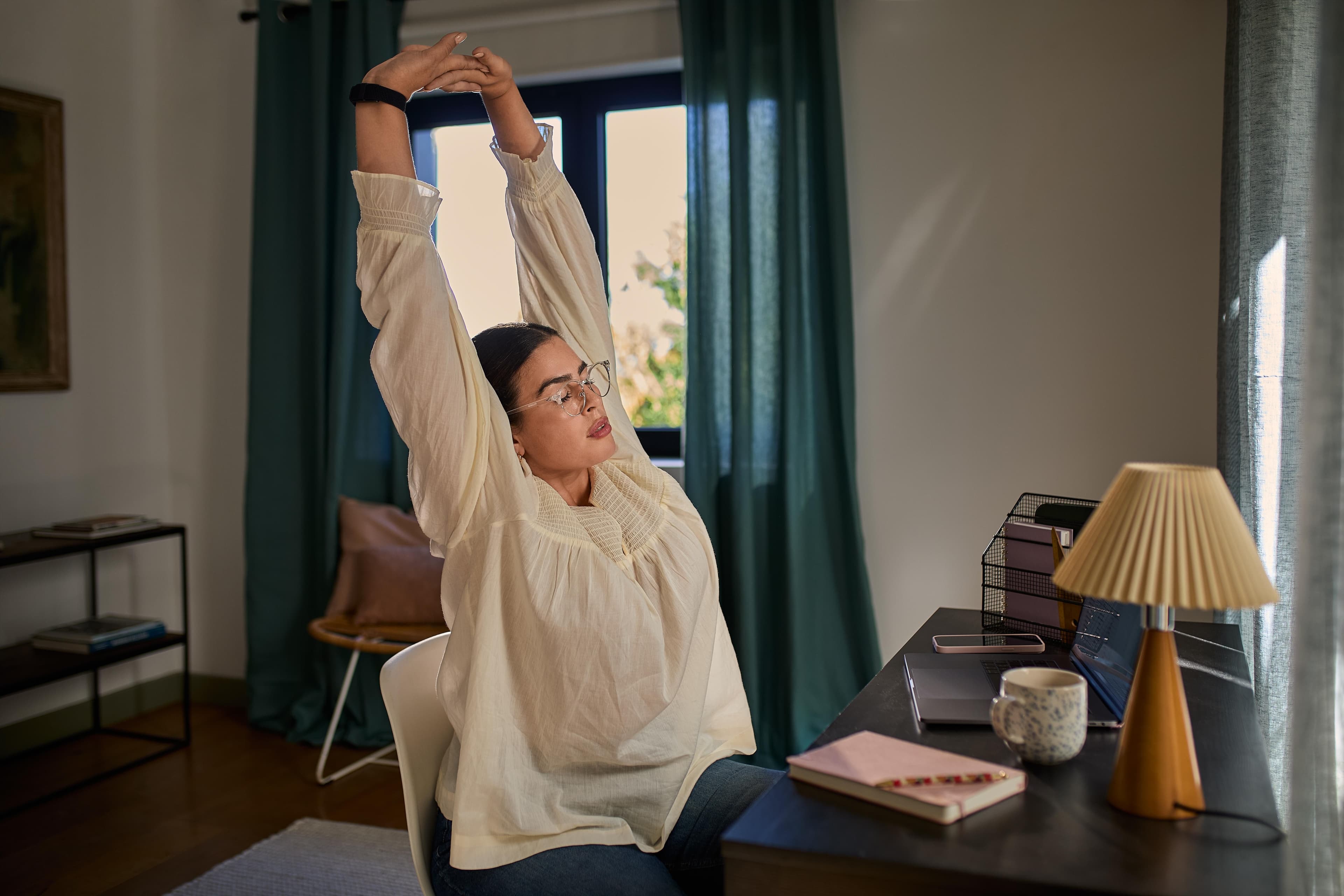 Woman stretching her back while sitting at a work desk