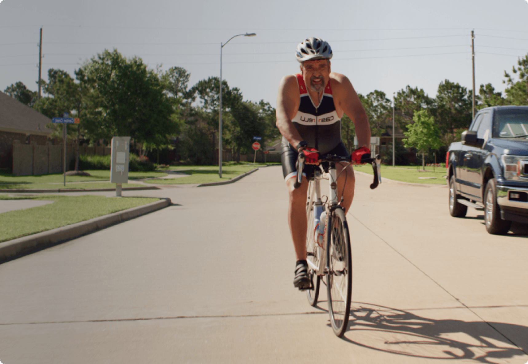 Man riding a road bike outside on a sunny residential street.